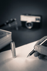 Man writing in a white diary with a silver fountain pen with gold details on a book. Business man desk, fountain pen, book, diary and photo camera.
Product photography black and gold fountain pen 