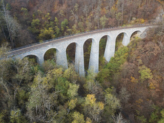 Aerial top view of stone Railway Viaduct near Prague, Czech republic. Old Czech railway line. Vintage arch bridge during autumn season.