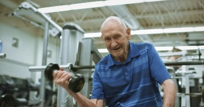 Tilt up, elderly man lights weights at gym