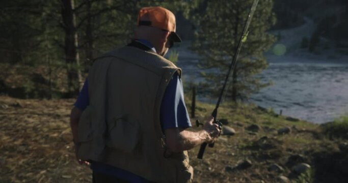 Elderly fisherman walks to river in Canada, tracking shot