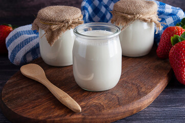Homemade yogurt made with fresh cow's milk and lactic ferments, wooden table and spoon, fresh...