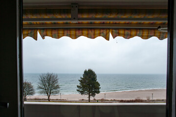 Blick unter Markise von Balkon auf den menschenleeren Strand der Ostsee