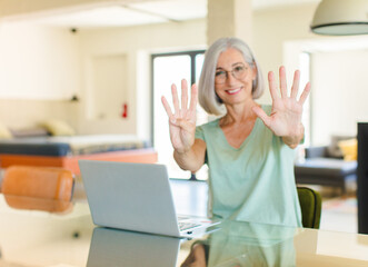 middle age woman smiling and looking friendly, showing number nine or ninth with hand forward,...