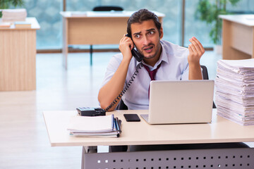 Young male employee unhappy with excessive work in the office