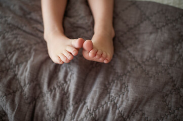 Toddler feet with toes touching on bed at home