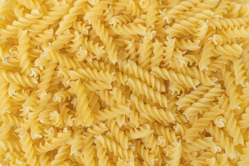Uncooked or dry fusilli type of pasta textured background.