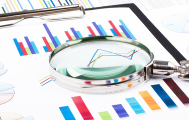Obraz premium Magnifying glass lying on business charts and graphs. Business planning,accounting,analysis,financial planning and data Analysis concept.