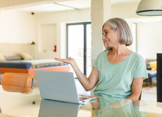 middle age woman feeling happy and smiling casually, looking to an object or concept held on the...