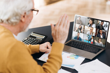 Video conference. Business partners communicate via video conference using laptop. The old...