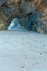 Traces of human feet in the sand against the background of a large stone on the ocean coast near the Portuguese city of Sintra