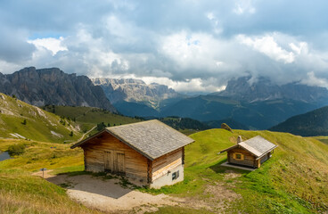 Fototapeta na wymiar Summer view of Seceda Odle Puez mountain and wooden chalets in Dolomites, Trentino Alto Adige, South Tyrol, Italy