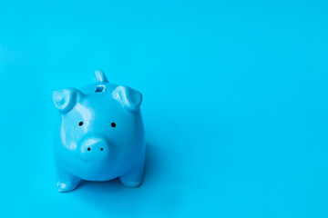 Blue piggy bank smile isolated on blue background. Finance, saving money concept.
