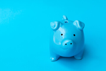 Blue piggy bank smile isolated on blue background. Finance, saving money concept.