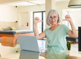 middle age woman feeling proud, arrogant and confident, looking satisfied and successful, pointing...