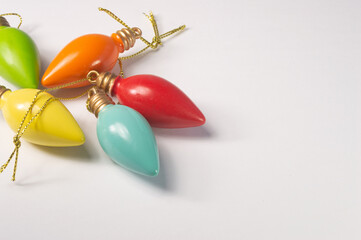 Multicolored bulb shaped Christmas ornaments laying on a white background