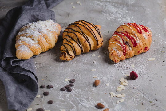 three fresh croissants on wooden board and cloth napkin