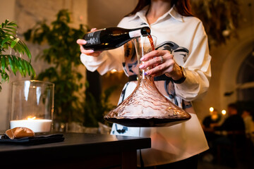 woman sommelier decanting red wine . woman sommelier pouring red wine into the decanter.  - obrazy, fototapety, plakaty