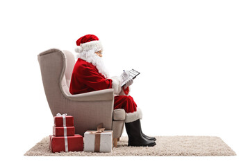 Profile shot of santa claus sitting in an armchair and writing a document