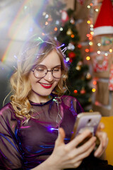 funny young Christmas girl taking selfie photo with mobile phone near Christmas tree