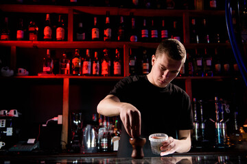 Barman fills black burnt ceramic bowl for hookah smoking different types of tobacco.