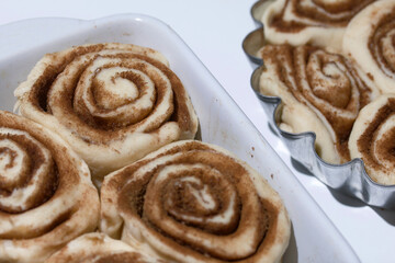 Baking cinnabons. The cinnamon dough is in the baking dish. Close-up shot.