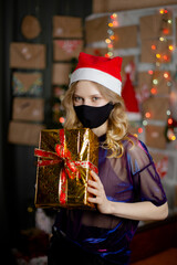 Portrait of a beautiful girl in medical mask, standing in front of decorated christmas tree at home