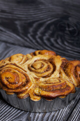 Baked cinnabons in shape. Stand on black composite boards. Close-up shot.