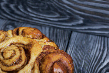 Baked cinnabons in shape. Stand on black composite boards. Close-up shot.