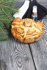 Baked cinnabons in shape. Stand on black pine planks. Nearby are spruce branches, medical masks and an antiseptic.