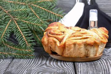 Baked cinnabons in shape. Stand on black pine planks. Nearby are spruce branches, medical masks and an antiseptic.
