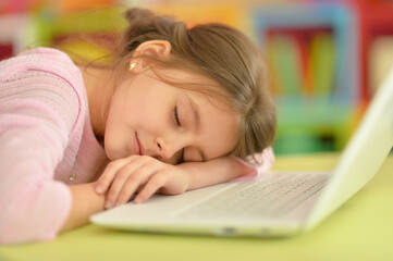 Portrait of cute girl sleeping on laptop at home