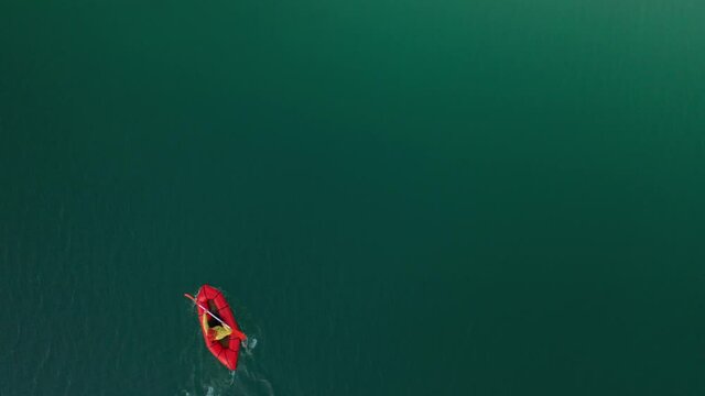 Packraft, one-person light raft used for expedition or adventure racing on a lake, inflatable boat Ride on a mountain lake. 4k aerial view