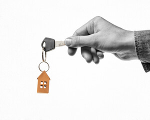 Key with orange paper house in human hand. Concept of rent, search, purchase real estate. Black and white