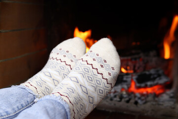 Feet in knitted socks at the fireplace on winter evening