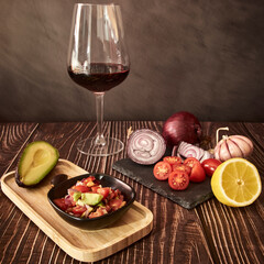 Guacamole ingredients on a wooden old table with a cup of red wine