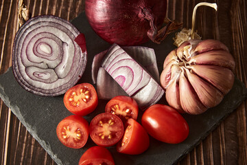 Tomatoes, garlic and onion on a wooden old table