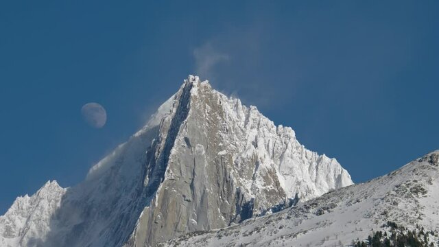 Moon behind the Aiguille Verte and Les Drus with windy plumes of snow