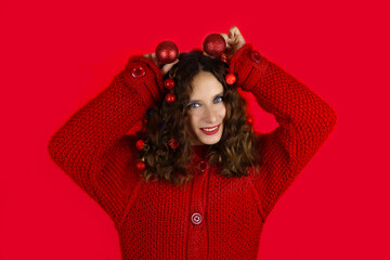 Beautiful girl with christmas toys in hair on red background
