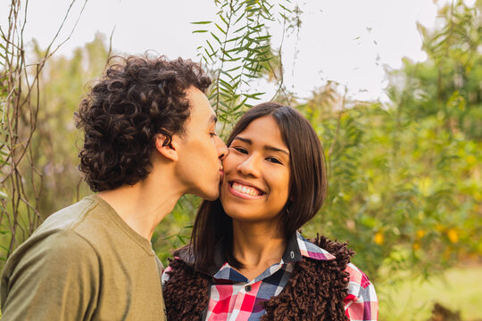 Image of a young and happy man kissing and hugging a beautiful woman - Portrait of a young brunette couple.