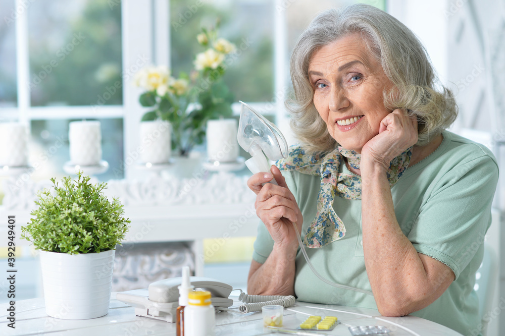 Sticker Sick senior woman sitting at kitchen with inhaler