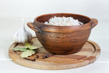 Sauerkraut in clay bowl. Homemade with carrot and salad cabbage on a wooden table.