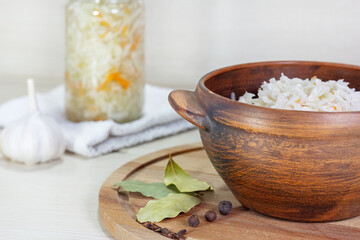 Fermented vegetables sauerkraut on wood background. Sauerkraut with carrot in wooden bowl, garlic, spices, cabbage..