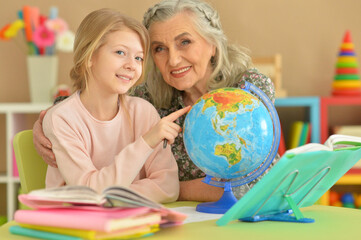 Grandmother with cute little girl doing homework