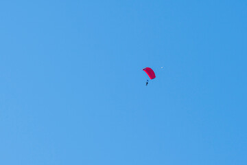 Tandem parachute jump. Silhouette of skydiver flying in blue clear sky