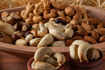 variety of nuts  in a wooden bowl and in two wooden cups with straw background. Main nuts of Brazilian cuisine.