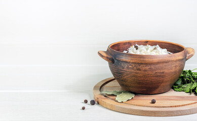 Homemade sauerkraut in a wooden bowl. Dish is decorated with a parsley, bay leaf and peppercorns. Fermented food.