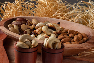 variety of nuts  in a wooden bowl and in two wooden cups with straw background. Main nuts of Brazilian cuisine.
