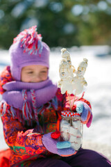 Little girl in winter in a snowy forest drinks hot cocoa. Christmas drink and snowman