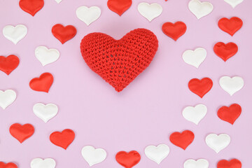 Pattern on a pink background of small red and white hearts with a big one in the center