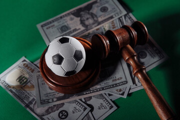 Soccer ball and judge gavel on green background close-up. Corruption in sports or betting concept.